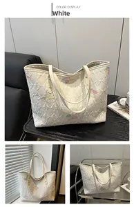 Dettaglio della borsa tote bianca con ricami a farfalla colorati e rivetti in metallo dorato