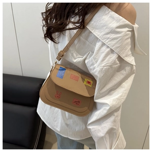 Khaki crossbody bag with colorful patches and rabbit print shown on model's shoulder