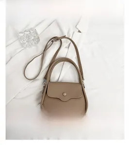 Top view of a khaki lychee pattern leather handbag on white textured fabric background