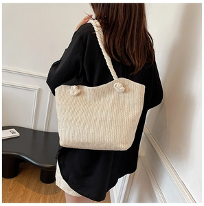 Detail of herringbone weave and knotted rope strap on a beige straw tote bag
