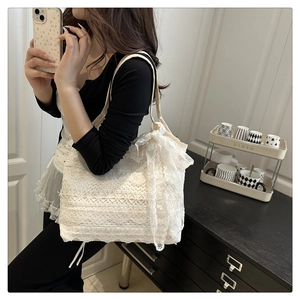 Detailed shot of beige lace tote bag with large decorative bow on a minimalist background