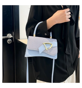 Detail view of light blue saddle bag featuring golden D-shaped buckle and textured fabric