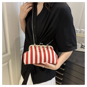 Detail of red and white striped crossbody bag with gold chain and vintage metal clasp