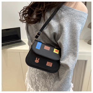Détail du sac bandoulière en cuir noir avec écussons de lapin mignon et de cœurs