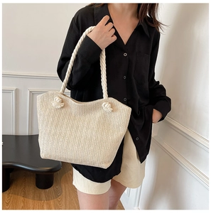 Detail of beige woven tote bag showing chevron texture and white cotton rope handles