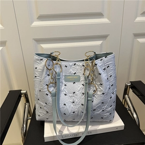 Light blue quilted tote bag with black bow embroidery and gold chain shoulder strap