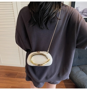 Back view of a chic white crossbody bag with gold metal ring details on a model