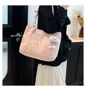 Detail of canvas tote bag featuring pink graffiti patterns and a plush cloud keychain