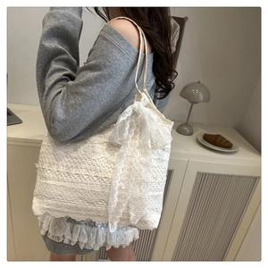 Close-up of white lace shoulder bag featuring a large decorative lace bow and texture