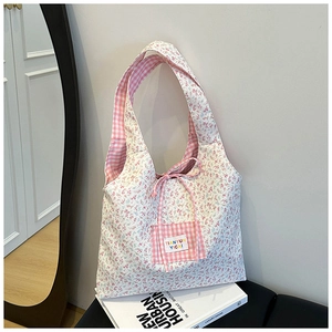 Détail du sac cabas en toile fleurie montrant la poche à carreaux et l'étiquette