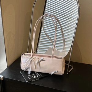 Pink balletcore shoulder bag with pearl bows and lace ribbons on black books