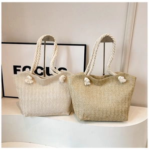 Detail of woven straw tote bags in beige and khaki with cotton rope handles