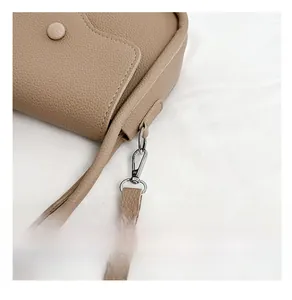 Detail of brown litchi pattern leather handbag featuring silver magnetic snap and metal hook