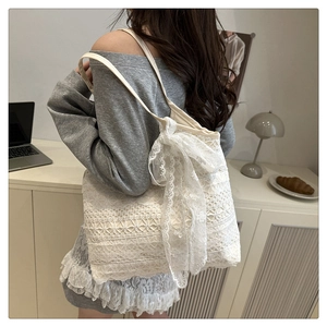Detail of white lace tote bag featuring intricate floral crochet patterns and a soft side bow