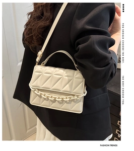 Close-up of white quilted crossbody bag with textured leather and gold chain detail