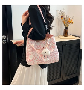 Detail of white tote bag with pink graffiti print and cloud charm in a home setting