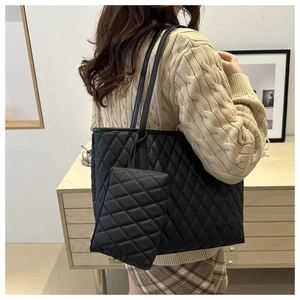 Close-up of quilted black tote bag with matching coin purse on a stylish shoulder strap
