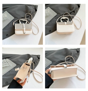 Detail view of cream crossbody bag featuring a unique heart-shaped silver metal handle