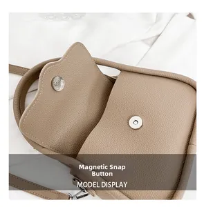 Detail view of khaki pebbled leather bag featuring a silver magnetic snap button closure