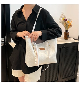 Detailed texture of white woven leather tote bag with logo patch and decorative tassel