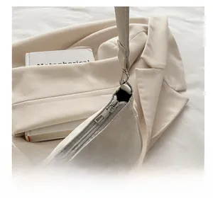 Détail de la fermeture éclair en métal argenté sur un sac à épaule blanc effet serpent