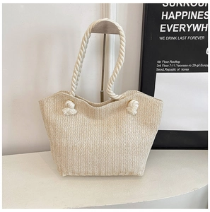 Detail of cream straw tote bag featuring herringbone weave and rope knot handles