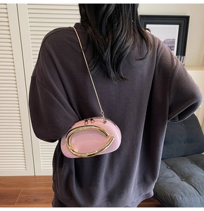 Pink semi-circle evening clutch bag with gold metal handle worn by a model