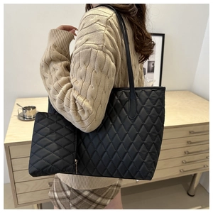 Detail of black quilted tote bag with matching small pouch and smooth shoulder strap