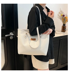 Detail of white woven texture tote bag with brown leather handles and large interior