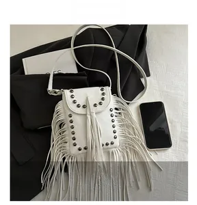 Detalle de bolso blanco con flecos, remaches metálicos y textura de cuero lichi