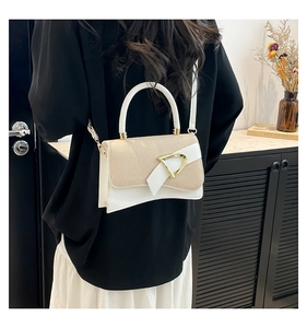 Detail of a white leather and beige woven handbag with golden D-clasp on model