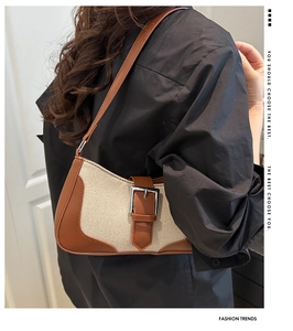 Close-up of crescent shoulder bag with beige canvas and brown leather trim details