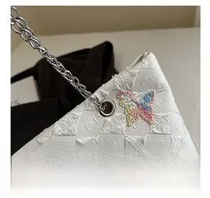 Detail of white tote bag featuring colorful butterfly embroidery and silver chain strap