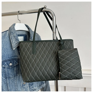 Detail of dark green quilted tote bag set with white diamond stitching and matching pouch