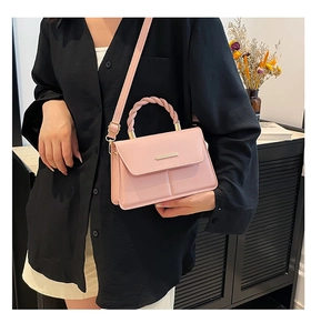 Pink PU leather crossbody bag with woven handle and gold trim detail on the flap