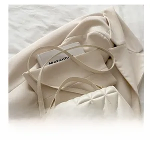 Close-up of beige quilted texture on square shoulder bag with elegant acrylic chain strap