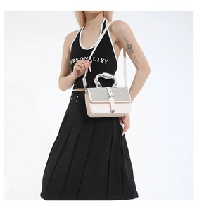 Detail of silver sequined flap and modern metallic handle on the beige crossbody bag