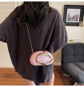 Pink leather shoulder bag detail with large gold C-shaped metal ring and chain strap