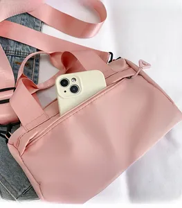 Détail d'un sac bandoulière en nylon rose montrant la poche zippée pour smartphone