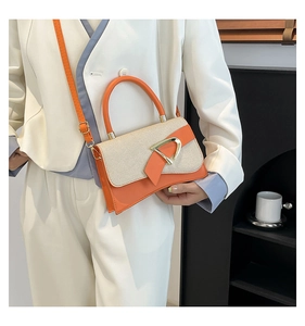 Detail of orange leather and woven fabric crossbody bag featuring a golden D-ring buckle