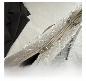Detail view of smooth zipper closure and silver metal chain strap on white tote bag
