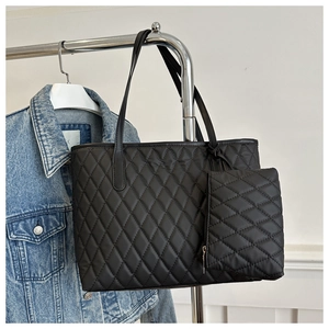 Detail of black quilted tote bag and matching pouch hanging on a blue denim jacket