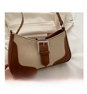 Close-up of beige linen underarm bag with brown leather trim and silver square buckle