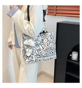 Close-up of graffiti print tote bag featuring black cartoon art and plush cloud charm