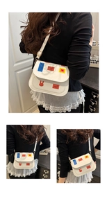 Detailed view of white PU leather crossbody bag featuring colorful artistic patch prints