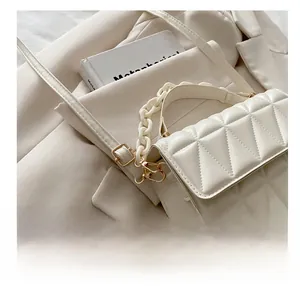Detailed shot of cream quilted bag texture with gold adjustment buckle and chain strap