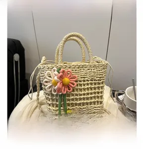 Detail of hand-woven straw bag featuring floral charms and secure drawstring closure