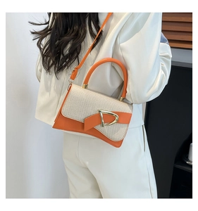 Detail of an orange leather and beige woven patchwork handbag with a gold D-ring buckle