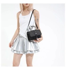 Detail of black leather handbag with sparkling sequin flap and silver heart-shaped handle