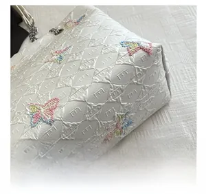 Detail shot of white quilted tote bag with multicolor butterfly embroidery and chain